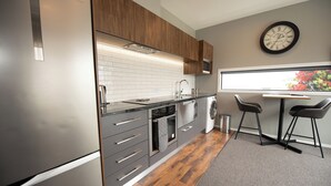 A modern kitchen with stainless steel appliances, wooden cabinets, and a large window with a view. - The Residence Apartment Two (New Plymouth)