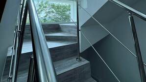 Eine moderne Treppe mit Metallgeländern und Blick ins Freie durch große Fenster.