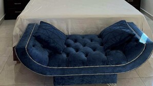 Ein Schlafzimmer mit einem großen Bett, zwei Nachttischen und einer blauen Polsterbank.