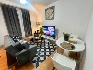 A modern living room with a sofa, a coffee table, a TV, and a small side table with a plant. - 2 bed Crew House Southampton Docks with Parking (Saint Denys)