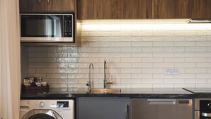 A compact kitchen with a built-in microwave, a dishwasher, and a stainless steel refrigerator. - The Residence Apartment Three (New Plymouth)