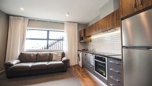 A modern kitchen with wooden cabinets, a stainless steel refrigerator, and a built-in oven. - The Residence Apartment Three (New Plymouth)