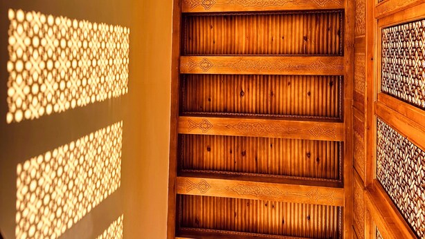 A wooden interior with a sloped ceiling and patterned wall panels. - Daro Hotel (Bukhara)