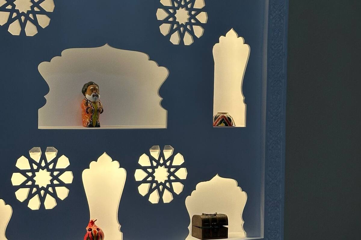 Quarto com painel decorativo que apresenta silhuetas recortadas de um camelo, um homem e uma mulher, juntamente com padrões geométricos.