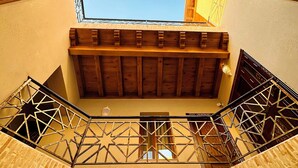 A high-ceilinged stairwell with wooden railings and a view of the sky through a window. - Daro Hotel (Bukhara)