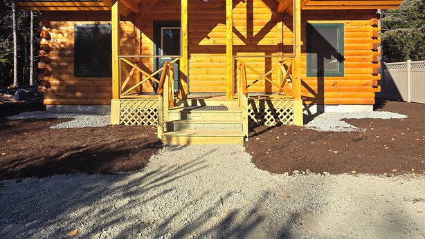 A log cabin with a porch, a chimney, and a door. -  3-bedroom Log Cabin with AC, WiFi ,Southwest Harbor
That Rents SAT-SAT ONLY (Southwest Harbor)