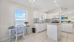 A modern kitchen with white cabinetry, a large island, and a view of the ocean. - Beautiful Direct Riverfront Paradise Home (Micco)