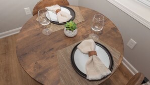 A round wooden dining table with a white plate, a small potted succulent, and two wine glasses. - Chic 1-bedroom with AC and WiFi in downtown Newnan (Newnan)