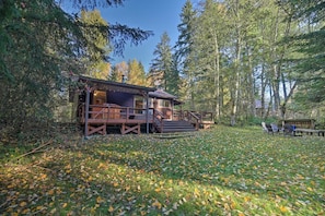 Une cabane dotée d’une terrasse, entourée d’arbres et située dans une zone boisée.