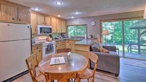 A kitchen with wooden cabinets, a dining table, and a view of the outdoors.
