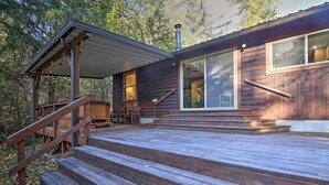 A wooden cabin with a deck, large windows, and a chimney.