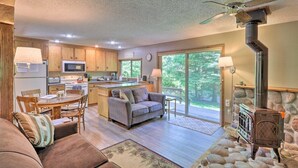 A modern kitchen with a central island, a dining area with a table and chairs, a living room with a sofa and a fireplace.