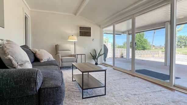 Una sala de estar con sofá, sillón y mesa de centro. Se aprecia una ventana con vistas al exterior.