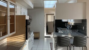 Una cocina moderna con una isla central, armarios blancos y vistas al salón.