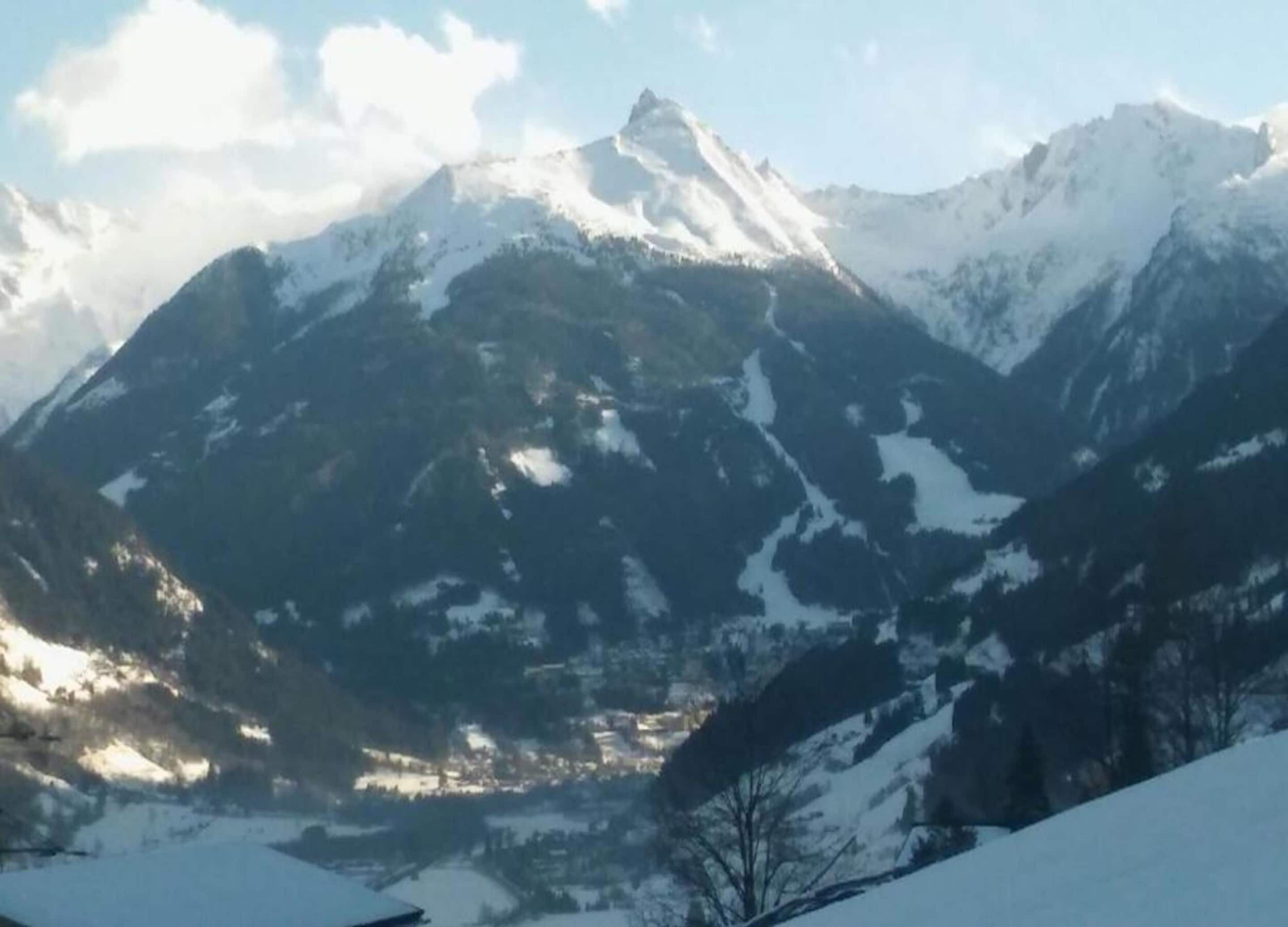 Un paysage de montagne avec des sommets enneigés et une vallée en contrebas.