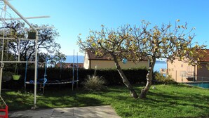 A backyard with a trampoline, a swing set, and a tree with yellow leaves. - Spacious Novi Vinodolski Apartments With Terrace and Shared Pool (Novi Vinodolski)