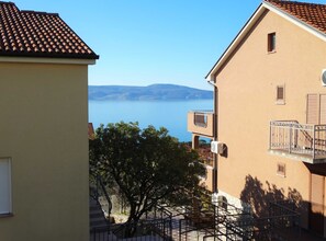 A building with a balcony overlooking a body of water and distant hills. - Spacious Novi Vinodolski Apartments With Terrace and Shared Pool (Novi Vinodolski)