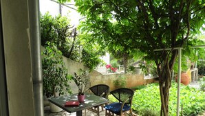 An outdoor seating area with a table and two chairs, surrounded by greenery and a stone wall. - Spacious Novi Vinodolski Apartments With Terrace and Shared Pool (Novi Vinodolski)