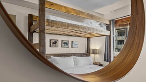Une chambre avec un lit superposé doté d’une tête de lit en bois, d’une lampe de chevet et de trois œuvres d’art murales sur le thème des animaux.