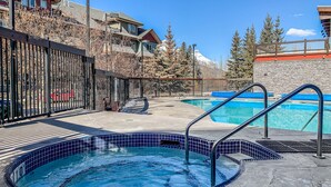 Un espace piscine comprenant un jacuzzi, une deuxième piscine et une vue sur une montagne.