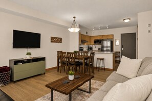 Una sala moderna con televisor, mesa de comedor de madera y sofá.