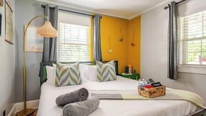 Un lit bien fait, avec des oreillers, une table de chevet avec une lampe et une fenêtre avec des rideaux.
