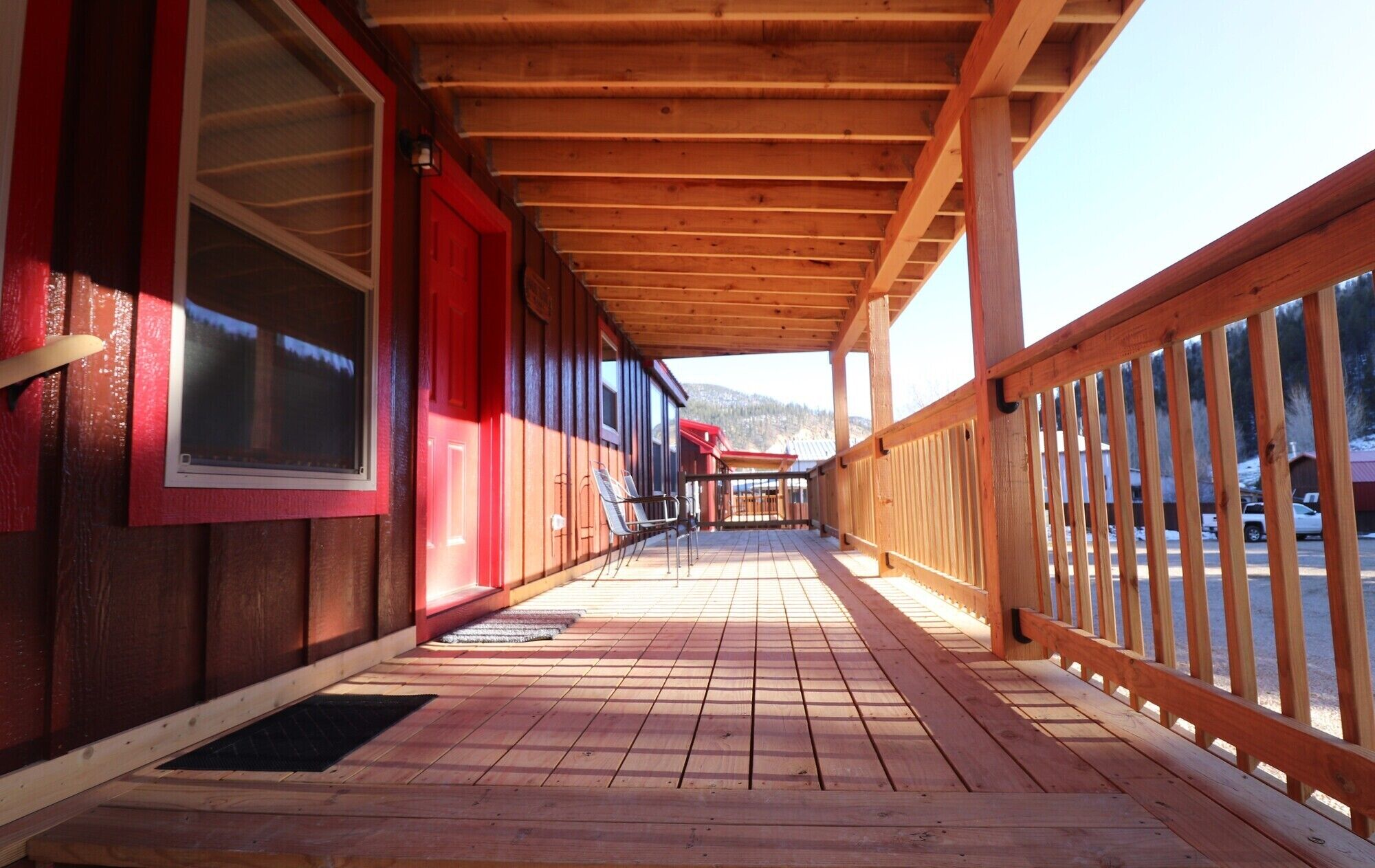 A wooden deck with a covered walkway, wooden railings, and a view of a snowy landscape.