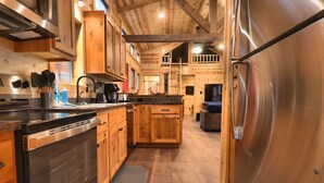 A modern kitchen with wooden cabinets, stainless steel appliances, and a wooden floor. - Golden Treasure Cabin (Red River)