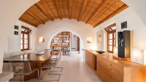 Eine geräumige Küche mit Holzbalkendecke, einer zentralen Kochinsel und einer integrierten Bücherwand.