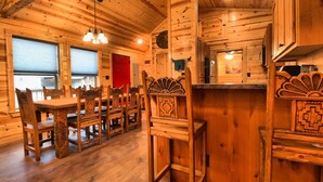 A wooden interior with a dining area, kitchen, and a red door. - Booker Retreat Cabin (Red River)