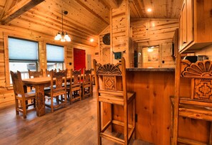 Cozy cabin interior with a wooden dining table and intricately carved chairs.
