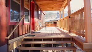A wooden deck with a staircase leading to a covered area with a view of a mountain. - Booker Retreat Cabin (Red River)