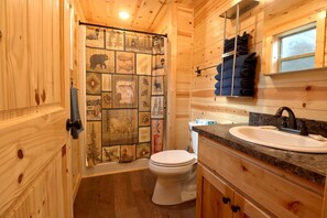 Features a compact bathroom with a toilet, sink, and shower curtain.