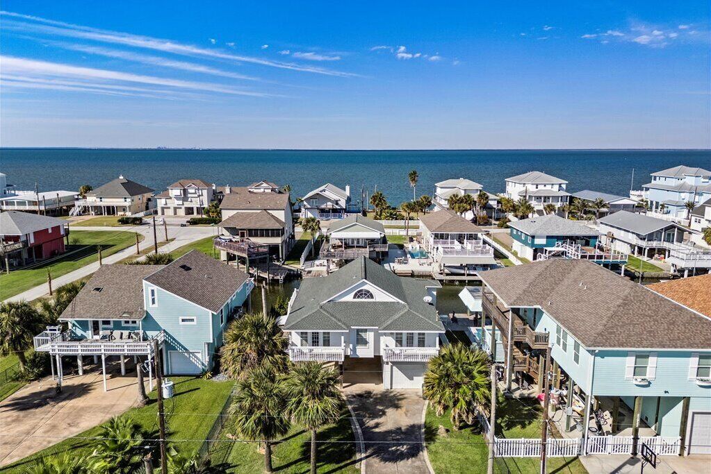 A coastal residential area with houses, some with attached docks, and a view of the ocean.