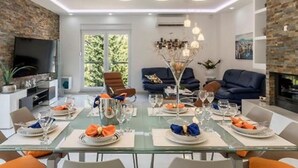 A modern dining area with a glass table set for a meal, surrounded by comfortable seating and a brick accent wall. - Modern & Stylish Villa with Private Pool - Four Bedroom Villa with Pool (Tugare)