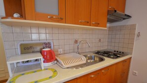 A compact kitchen with wooden cabinets, a sink, a stove, and a coffee machine. - Sleek and Serene Flat and Rooms - Studio Apartment with Terrace (Rovinj)
