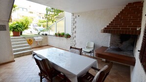 An outdoor patio with a table and chairs, a brick fireplace, and a view of the street. - Sleek and Serene Flat and Rooms - Studio Apartment with Terrace (Rovinj)