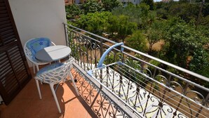 Ein Balkon mit Metallgeländer, einem kleinen Tisch und einem Stuhl.