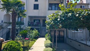 Ein Innenhof mit einem zentralen Weg, umgeben von Gebäuden mit Balkonen und einer Palme.
