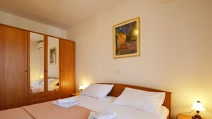 Une chambre d’hôtel avec un grand lit, une armoire en bois, une lampe de chevet et un tableau au mur.