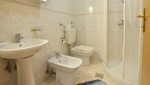 Une salle de bain équipée d’un lavabo, d’un bidet, de toilettes et d’une douche à parois en verre.