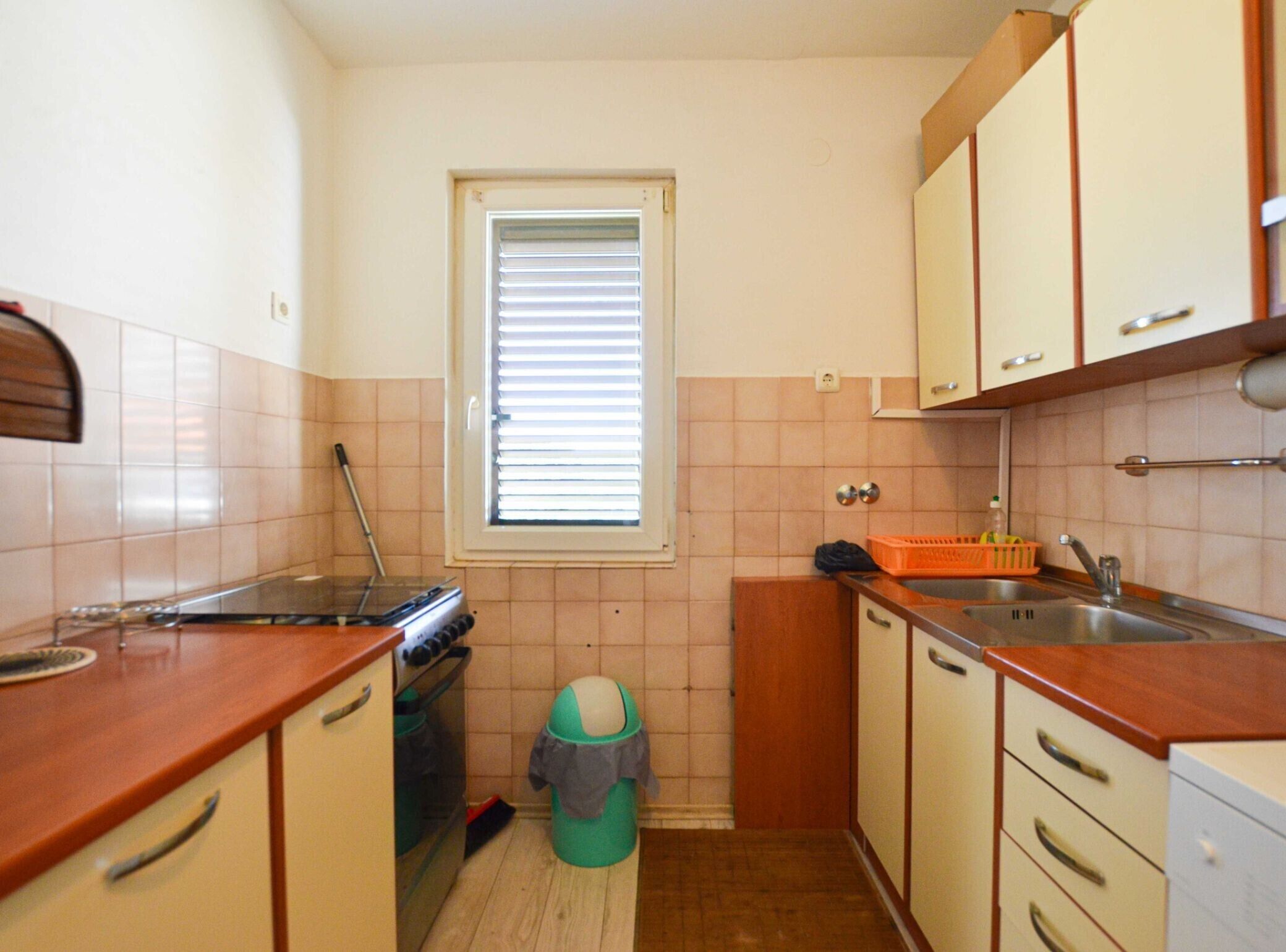 Una cocina pequeña con ventana, un lavamanos y armarios.