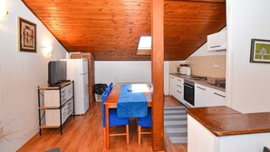 Una cocina compacta con vigas de madera, una mesa de comedor con mantel azul y un refrigerador.
