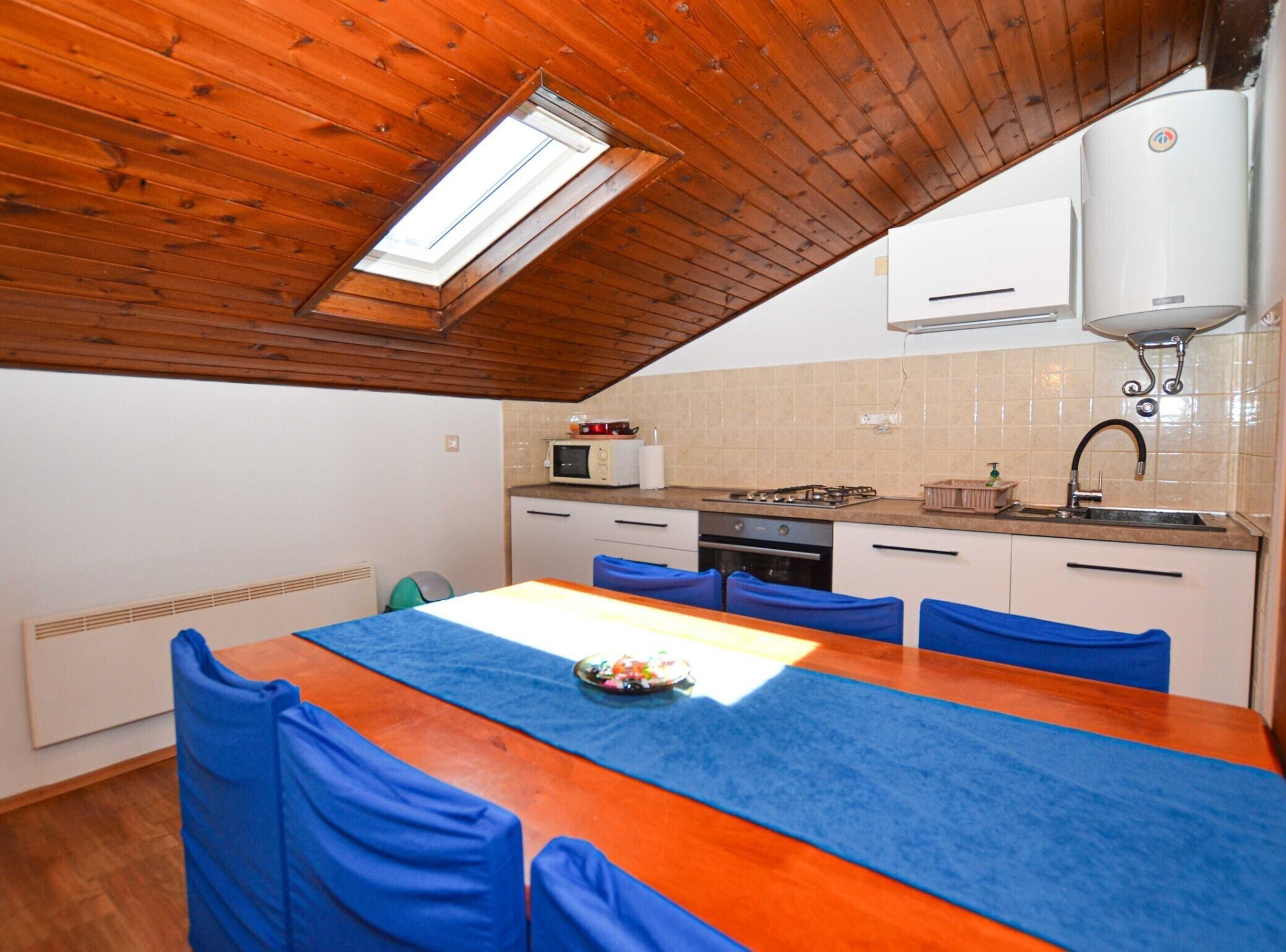 Cocina compacta con comedor, que cuenta con techo de madera, tragaluz, microondas, estufa y pileta.