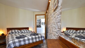Une chambre à coucher avec une couvre-lit à carreaux, une tête de lit en bois et un mur d’accent en pierre.