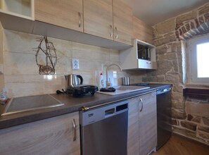 Een koelkast, een kookplaat, een vaatwasser, kookgerei, borden en bestek