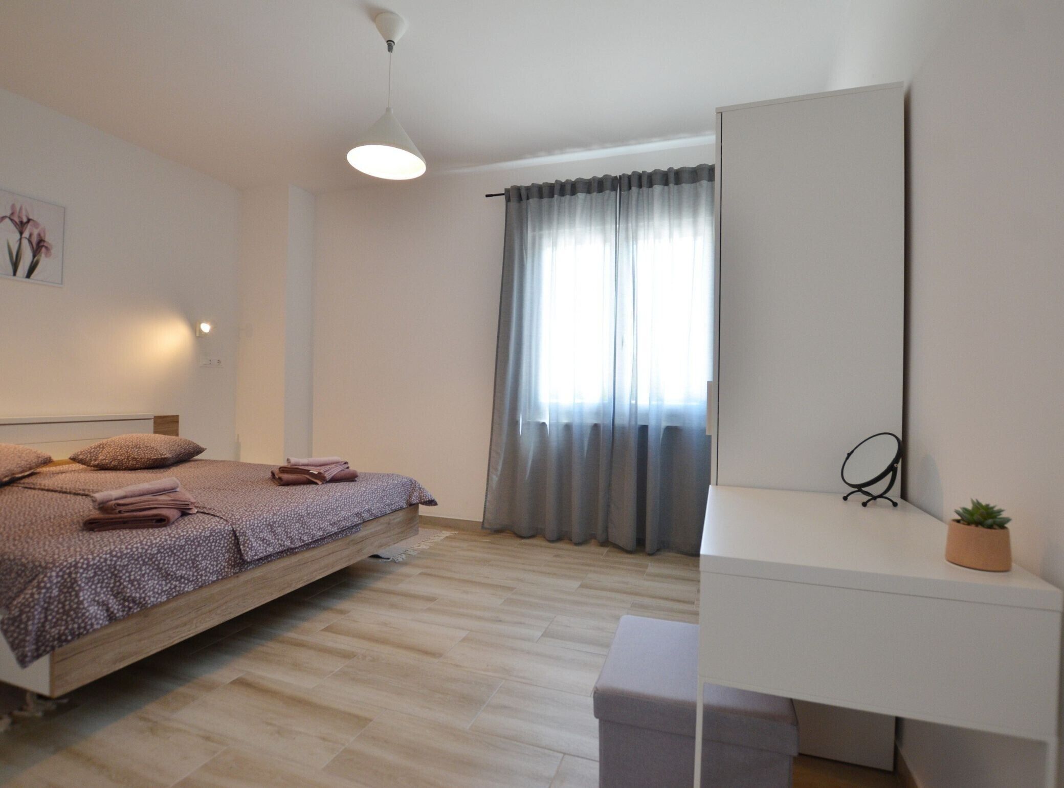 Een slaapkamer met een bed, nachtkastje en spiegel.