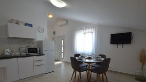 Una cocina moderna con comedor, televisor de pantalla plana y un amplio ventanal.