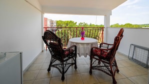 A balcony with two wicker chairs, a small round table, and a red railing.