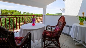 A balcony with a table and chairs, a railing, and a view of greenery and buildings.